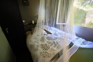 a bedroom with a bed with a curtain and a window at Gîte Un chalet en Sidobre in Lacrouzette
