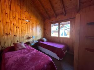 Un dormitorio con dos camas en una cabaña de madera. en Casita Roca - Pleno Centro, en San Martín de los Andes