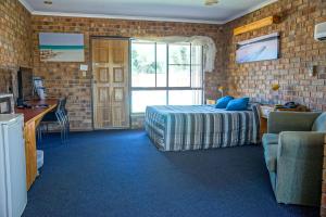 a bedroom with a bed and a brick wall at Kadina Gateway Motor Inn in Kadina