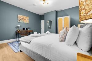 ein Schlafzimmer mit einem großen weißen Bett mit blauen Wänden in der Unterkunft 3-Bedroom Stunning, Cosy, Luxurious House in Fratton, Sleeps 8 with Parking, Pet-Friendly - LONG TERM STAY SPECIAL OFFER AVAILABLE! - by Blue Puffin Stays in Portsmouth