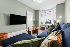 ein Wohnzimmer mit einem blauen Sofa und einem Flachbild-TV in der Unterkunft 3-Bedroom Stunning, Cosy, Luxurious House in Fratton, Sleeps 8 with Parking, Pet-Friendly - LONG TERM STAY SPECIAL OFFER AVAILABLE! - by Blue Puffin Stays in Portsmouth