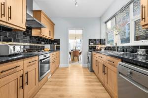 eine Küche mit Holzschränken und schwarzen Arbeitsplatten in der Unterkunft 3-Bedroom Stunning, Cosy, Luxurious House in Fratton, Sleeps 8 with Parking, Pet-Friendly - LONG TERM STAY SPECIAL OFFER AVAILABLE! - by Blue Puffin Stays in Portsmouth