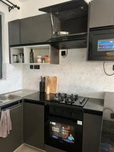 eine Küche mit einem schwarzen Herd und einer Mikrowelle in der Unterkunft Kitisuru Zen Stay in Gatunga + 7 Fotos