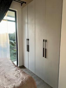 ein Schlafzimmer mit weißen Schränken und einem großen Fenster in der Unterkunft Kitisuru Zen Stay in Gatunga