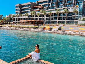Eine Frau, die auf einem Floß im Wasser in einem Resort sitzt. in der Unterkunft The Bodrum Hotel Yalıkavak - MGallery Collection in Yalıkavak