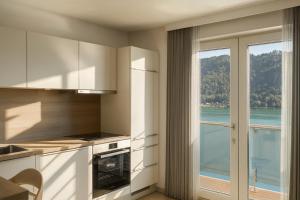 a kitchen with white cabinets and a view of the water at Lake Lodge Ossiacher See in Annenheim +3 photos
