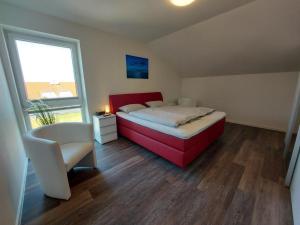 a bedroom with a bed and a chair and a window at Neue Liebe Haffkrug 5 - Meeresstern in Haffkrug