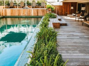 a swimming pool with benches next to a wooden deck at Costanero Hotel Montevideo - MGallery Collection in Montevideo