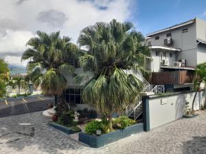 two palm trees in front of a building at Christar Villas Hotel in Kingston