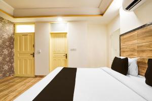 a bedroom with a white bed and a yellow door at Hotel O Pragati in Jairāmpura