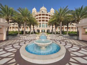 une fontaine devant un bâtiment avec des palmiers dans l'établissement Raffles The Palm, à Dubaï