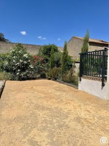 Un patio de tierra con una cerca y algunas flores. en Sous les toits, en Canet d'Aude