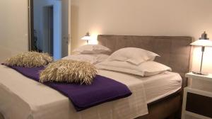 a large bed with white pillows and purple sheets at Stars Palace - apartments and rooms in Jezera +145 photos
