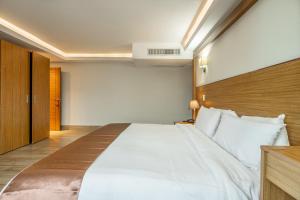 a bedroom with a large white bed with a wooden headboard at Weston Suites Hotel in Santo Domingo +55 photos