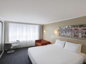 a hotel room with a white bed and a table at Mercure Newcastle in Newcastle