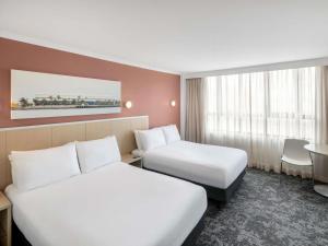 a hotel room with two beds and a table at Mercure Newcastle in Newcastle +109 photos