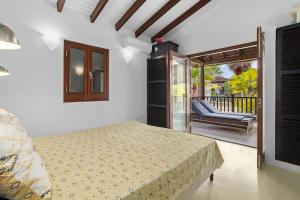 1 Schlafzimmer mit einem Bett und einem Balkon mit einem Stuhl in der Unterkunft 3bdr, with tropical garden & pool in Kralendijk! in Kralendijk