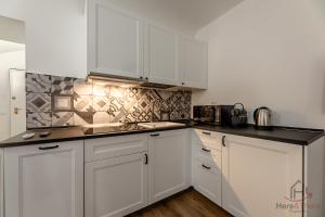 una cucina bianca con mobili bianchi e ripiani neri di The Heart of Savona B - Free Parking - Cruise 2min a Savona Altre 16 foto