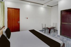 バラナシにあるHotel O Ujala Guest Houseのベッドルーム1室(ベッド1台、ドア、テーブル付)