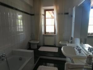 a white bathroom with a tub and a sink at La Terrazza di Maria in Pienza