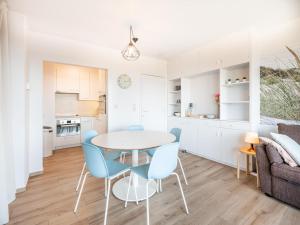 een witte keuken en een eetkamer met een tafel en stoelen bij Manderley tweede in Oostduinkerke-Bad