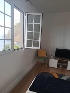 a white room with a tv and two windows at Dhamma Guest House in Ponta Delgada +7 photos