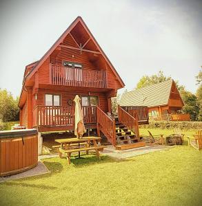 a wooden house with a picnic table and a bench at Luxury Waterfront Retreat I Deluxe Lodge I Private Hot Tub & Sauna in Belturbet
