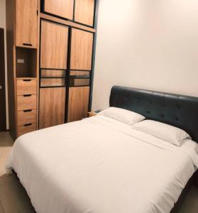 a bedroom with a white bed and a wooden cabinet at T'garden Homestay in Batu Pahat