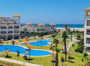a view of a resort with a slide and the beach at BERALMAR CHEZ HOUDA VACANCES PIEDS DANS l' EAU in Asilah