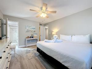 a bedroom with a white bed with a ceiling fan at Waves 9 in St Pete Beach +147 photos