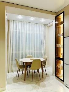 a dining room with a table and chairs and a window at K7 Family in Atyraū