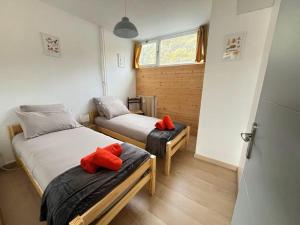 two beds in a room with red pillows on them at A l'orée des bois in Égat