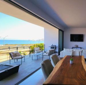 a living room with a table and chairs and a large window at Luxury apartment overlooking the Arch in Cabo San Lucas
