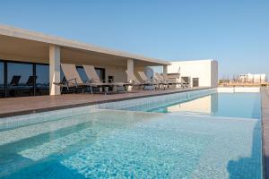 a swimming pool with chairs on a building at Luxury apartment overlooking the Arch in Cabo San Lucas