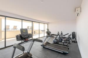 a gym with three cardio machines and a large window at Luxury apartment overlooking the Arch in Cabo San Lucas