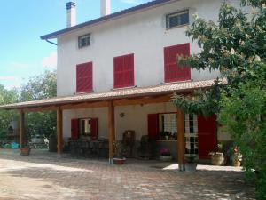 Una casa blanca con persianas rojas. en B&B Da Mariella en Spigno Saturnia