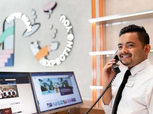 a man talking on a phone in front of a computer at ibis Styles Sydney Central in Sydney
