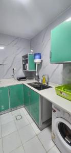 una pequeña cocina con armarios verdes y fregadero en Sky chalet, en Sur