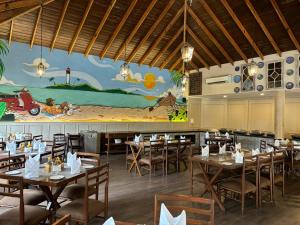 a dining room with tables and chairs and a mural at Amritara Aura Resort & Spa in Mandrem