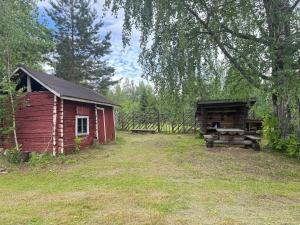 a red barn and a shed in a field at Mummon mökki in Mäntylahti