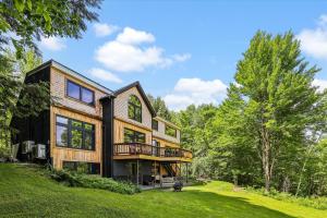 a large house with a deck on a lawn at Green Mountain Haus in Stowe