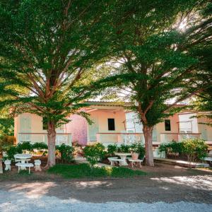 a group of picnic tables and trees in front of a building at บ้านพักหน้าหาดชะอำใต้ in Ban Sahakham