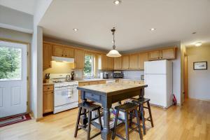 a kitchen with wooden cabinets and a table with stools at Four Seasons Chalet in Waterbury Center