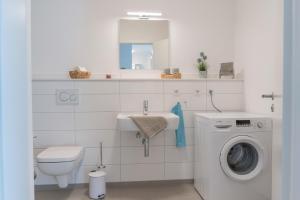 a bathroom with a washing machine and a sink at Inselblume 43 - Zentrumsnahe, moderne Ferienwohnung in Burg in Burg auf Fehmarn