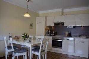a kitchen with a table and chairs and a kitchen with white cabinets at Inselblume 07 - Ferienwohnung mit Hund an der Reiterkoppel in Neue Tiefe Fehmarn +16 photos