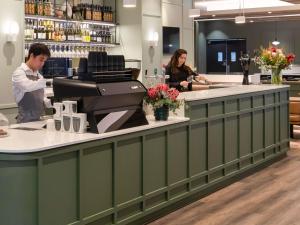 dos personas de pie en el mostrador de un bar en Mercure Melbourne Southbank, en Melbourne