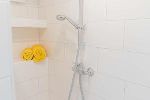 a shower with a yellow towel and a shower head at Inselblume 66 - Kuschlige Ferienwohnung für 2 in Landkirchen in Landkirchen