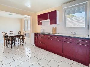 a kitchen with red cabinets and a table with chairs at Le campagnard in Gavrelle