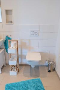 a bathroom with a toilet and a blue rug at Inselblume 47 - Luxus Ferienwohnung in Burg, mit Dachterrasse in Burg auf Fehmarn +9 photos