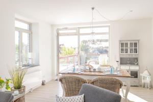 a white kitchen with a table and chairs at Inselblume 47 - Luxus Ferienwohnung in Burg, mit Dachterrasse in Burg auf Fehmarn
